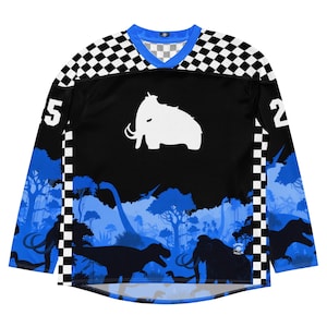 Puede incluir: Camiseta negra de manga larga con un estampado de cuadros azules y blancos en los hombros y las mangas. La camiseta presenta un gráfico de mamut blanco y un diseño de paisaje prehistórico azul. Los números 5 y 2 están en las mangas.