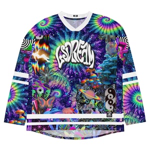 May include: A long-sleeved jersey with a vibrant tie-dye design in shades of blue, purple, and green. The word "LSDREAM" is displayed in white across the chest. The jersey features white stripes on the sleeves and a white V-neck collar.