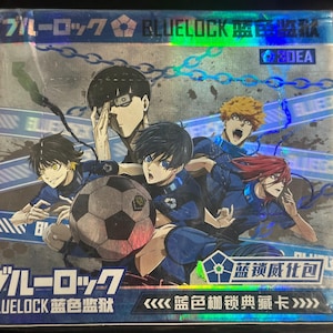 Puede incluir: Una caja de cartas coleccionables con la serie de anime "Blue Lock". La caja tiene un acabado hologr&aacute;fico y muestra varios personajes de anime con uniformes azules, con un bal&oacute;n de f&uacute;tbol en el centro. El texto japon&eacute;s es visible en la parte superior e inferior de la caja.