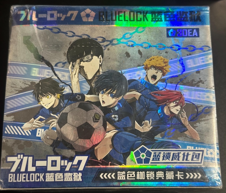 Puede incluir: Una caja de cartas coleccionables con la serie de anime "Blue Lock". La caja tiene un acabado hologr&aacute;fico y muestra varios personajes de anime con uniformes azules, con un bal&oacute;n de f&uacute;tbol en el centro. El texto japon&eacute;s es visible en la parte superior e inferior de la caja.