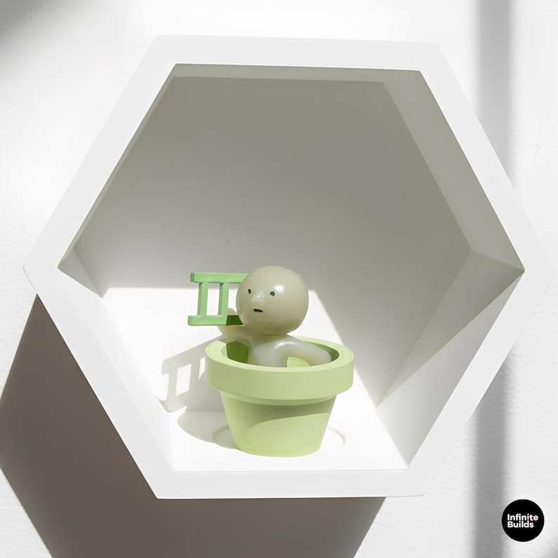 May include: A white hexagonal shelf displays a light green figurine in a light green flower pot, holding a small green ladder. The figurine has a round head and a neutral expression. The shelf is mounted on a white wall.