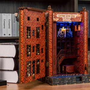 Pode incluir: Diorama detalhado de livro aberto com fachada de tijolos, apresentando um interior de loja com escada e candelabro. O diorama &eacute; iluminado com luzes azuis e amarelas, com o texto "Enchanted Wood Shop".