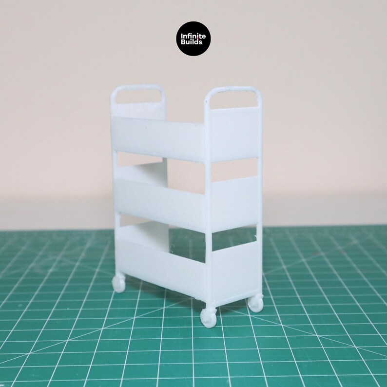 May include: White metal rolling cart with three shelves. The cart has a simple design and is perfect for organizing small items.