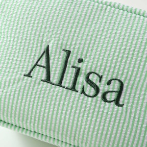 May include: A green and white striped fabric tote bag with the name "Alisa" embroidered in dark green thread.