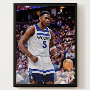 Pode incluir: Um jogador de basquete vestindo uma camisa branca com detalhes azuis e a palavra "WOLVES" e o número "5" na frente. O jogador está driblando uma bola de basquete na frente de uma multidão de fãs.