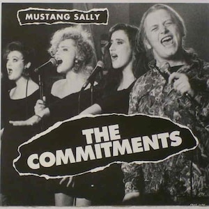 May include: Black and white photo of a band called "The Commitments" performing the song "Mustang Sally". The band is made up of four people, three women and one man. The women are singing into microphones and the man is playing a guitar.