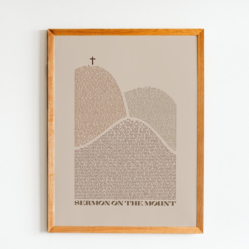 May include: A beige framed print with a brown silhouette of two mountains formed by the text of the Sermon on the Mount. The text is in a serif font and the title "Sermon on the Mount" is at the bottom of the print.