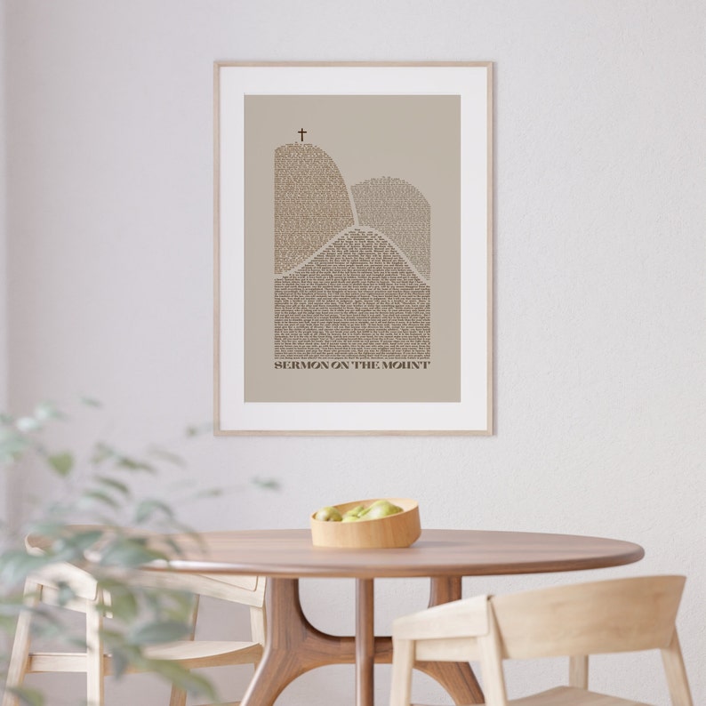 May include: A framed print with a beige background featuring a stylized depiction of two mountains with the text "SERMON ON THE MOUNT" at the bottom. A cross is at the peak of the tallest mountain.