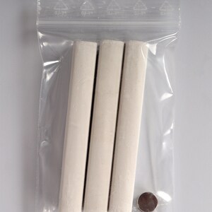 May include: Three white chalk sticks in a clear plastic bag with a small silver disc.