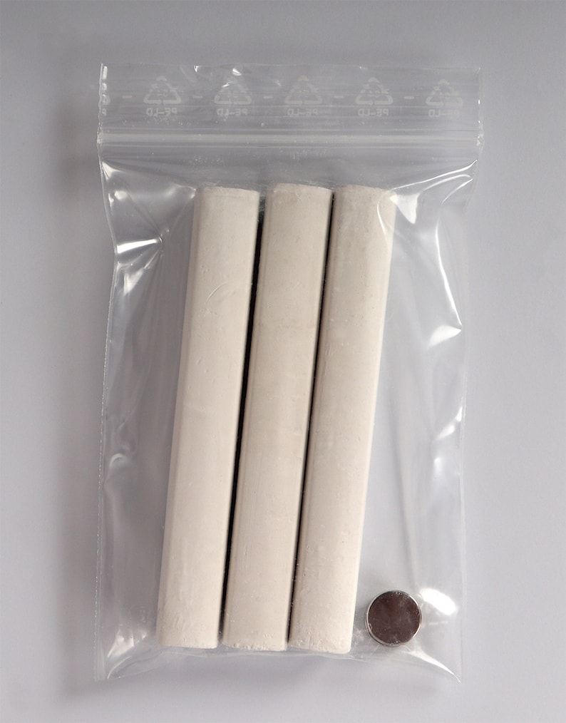 May include: Three white chalk sticks in a clear plastic bag with a small silver disc.