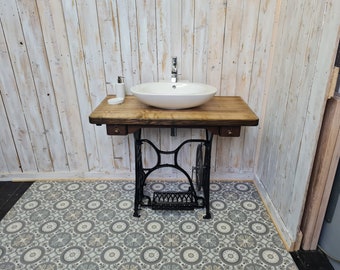 May include: A white porcelain sink with a chrome faucet sits on a wooden countertop with a black metal base. The countertop is supported by a black metal frame with a wheel on one side. The sink is in a bathroom with white wood paneling and patterned tile flooring.