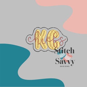 May include: A gold embroidered design with the letters "KC" and the word "Chiefs" in a cloud shape, outlined in black. The design is on a gray background with pink and teal shapes. The text "Stitch Savvy Designs" is below.