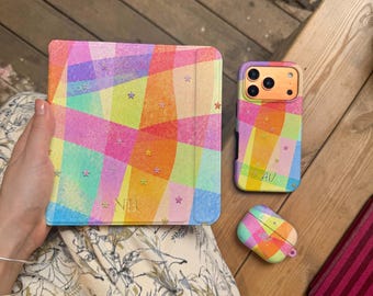 May include: A square tablet case, a rectangular smartphone case, and a small rectangular earbud case, all featuring a vibrant, multi-coloured geometric pattern with a glittery finish and small star accents. The tablet case is embossed with the letters NB.
