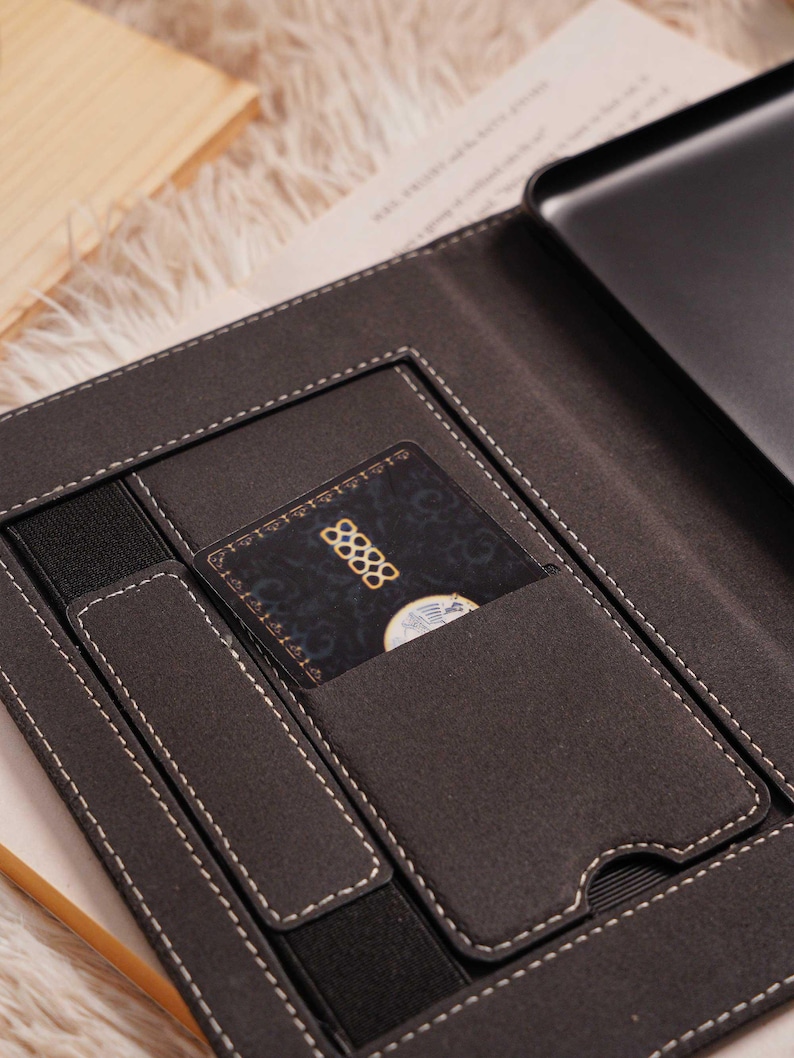 May include: Dark gray laptop sleeve with white stitching and multiple pockets. A credit card with the number 88888 is visible in one of the pockets. The sleeve is open, revealing a laptop inside.