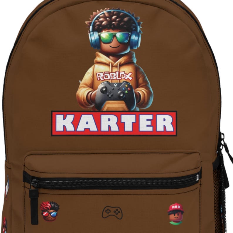 Pode incluir: Mochila marrom com uma ilustra&ccedil;&atilde;o de desenho animado de um personagem usando fones de ouvido e &oacute;culos de sol, segurando um controle de jogo. O nome "KARTER" &eacute; exibido em uma caixa vermelha e branca. Pequenos gr&aacute;ficos de controles de jogo e um personagem est&atilde;o na frente.