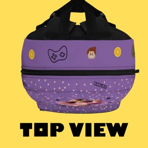 May include: Purple and black backpack with a gamer theme. It features a video game controller, a Roblox logo, and a cartoon character. The backpack has a zippered pocket and a small pocket on the front.
