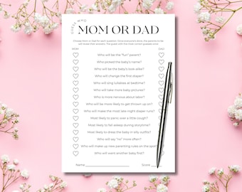 May include: A white rectangular game card titled Guess Who Mom or Dad with a list of questions and heart-shaped checkboxes for answers. A silver ballpoint pen rests on the right side of the paper, which features black text on a white background.