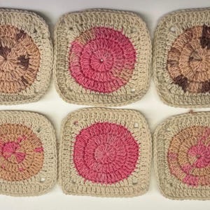 May include: Six handmade crochet squares. Each square features a central circular design in shades of pink, brown, and beige, surrounded by a beige border. The squares are arranged in two rows of three.