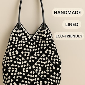 Może przedstawiać: Czarna i biała szydełkowa torba typu tote z czarnymi skórzanymi uchwytami. Torba ma wzór w kropki i tekst "HANDMADE", "LINED" i "ECO-FRIENDLY".
