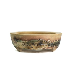 May include: A handcrafted, oval-shaped bonsai pot. The ceramic pot features a textured surface with a blend of earthy tones, including beige, brown, and green. It rests on three small feet, adding to its unique design.