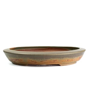 May include: An oval-shaped ceramic bonsai pot with a low profile and a wide rim. The exterior features a muted olive green glaze that transitions into a textured, earthy terracotta brown base. The interior is a smooth, deep reddish-brown clay.