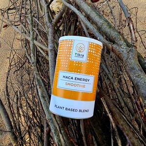 May include: A yellow and white cylindrical container with the text "Tikra Superfoods Maca Energy Smoothie Plant Based Blend" on it. The container is sitting on a pile of brown branches.