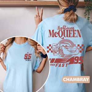 May include: A light blue t-shirt featuring a red graphic of Lightning McQueen from the Cars film. The graphic includes the text "Lightning McQueen", "95", and "Kachow!" The shirt is made from a soft, comfortable fabric and is ideal for fans of the Cars franchise.
