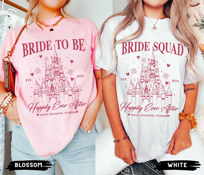 K&ouml;nnte beinhalten: Zwei wei&szlig;e T-Shirts mit einem rosa und wei&szlig;en Design von Cinderellas Schloss. Der Text auf den Shirts lautet "Bride to Be" und "Bride Squad" mit den Worten "Happily Ever After" und "Magic Kingdom, Florida" unterhalb des Schlosses. Die Shirts werden von Models getragen, die Jeans tragen.