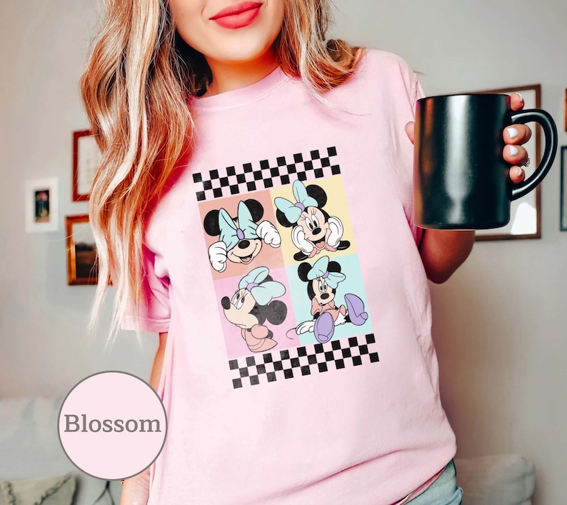 May include: Pink t-shirt featuring a checkered pattern and four images of Minnie Mouse in various poses. The images are arranged in a grid pattern, each with a different coloured background.