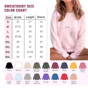 May include: A light pink sweatshirt with a size chart and color options. The chart lists sizes S to 5XL, with measurements in inches for width, length, and sleeve length. Color options include black, white, sand, military green, forest green, maroon, navy, gold, and safety pink.