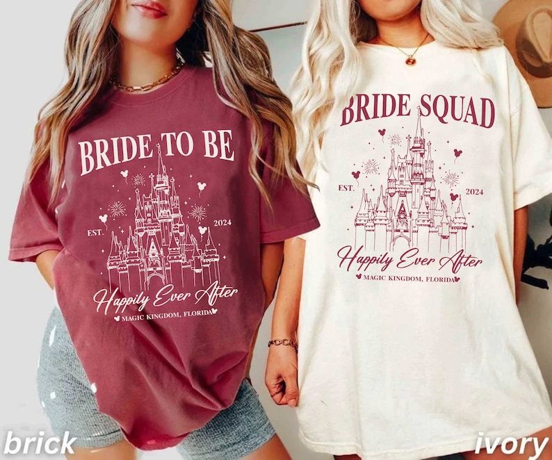 K&ouml;nnte beinhalten: Zwei T-Shirts mit einem wei&szlig;en Motiv von Schloss Aschenputtel auf einem burgunderfarbenen und elfenbeinfarbenen Hintergrund. Der Text auf dem burgunderfarbenen Shirt lautet "Bride to Be" und "Happily Ever After" mit dem Jahr "2024" und "EST.". Der Text auf dem elfenbeinfarbenen Shirt lautet "Bride Squad" und "Happily Ever After" mit dem Jahr "2024" und "EST."