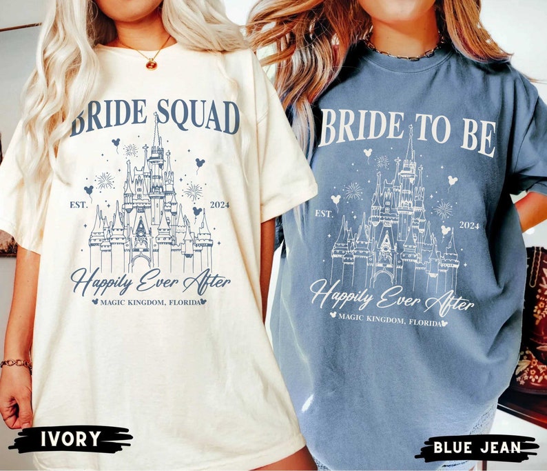 K&ouml;nnte beinhalten: Zwei T-Shirts mit einer wei&szlig;en Umrandung von Cinderellas Schloss, Feuerwerk und Mickey-Maus-Ohren. Der Text auf dem elfenbeinfarbenen Shirt lautet "Bride Squad Est. 2024 Happily Ever After Magic Kingdom, Florida". Der Text auf dem Jeans-Shirt lautet "Bride to Be Est. 2024 Happily Ever After Magic Kingdom, Florida".