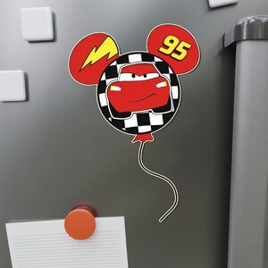 K&ouml;nnte beinhalten: Rotes Rennwagen mit einem Blitz und der Nummer 95 auf einem schwarz-wei&szlig; karierten Ballon in Form von Mickey-Maus-Ohren.