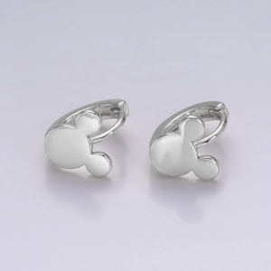 Op de afbeelding: Een paar zilverkleurige oorringen, elk in de vorm van een Mickey Mouse-hoofd. De oorbellen hebben een gladde, gepolijste afwerking en een eenvoudig ontwerp. Ze worden gepresenteerd tegen een lichte achtergrond.