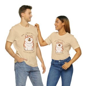 May include: Two beige t-shirts with a cartoon Shiba Inu dog wearing a red collar and the text "Damn... I might have to call in thicc today".