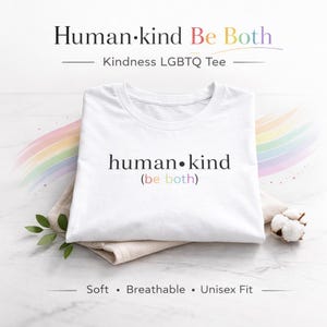 May include: A white t-shirt with the text "human•kind (be both)" in black and rainbow colors. The shirt is part of the Kindness LGBTQ Tee collection. The words "Soft, Breathable, Unisex Fit" are printed at the bottom.
