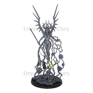 Op de afbeelding: Een grijze plastic miniatuur van een vrouwelijke figuur met vleugels, die een speer vasthoudt en op een basis met wijnstokken en bloemen staat. De figuur draagt een vloeiende jurk en een kroon op haar hoofd.