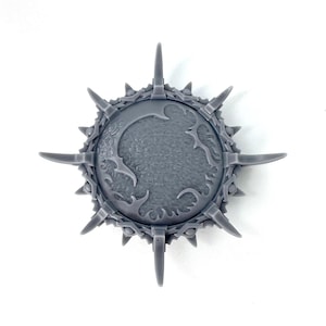 May include: A gray plastic shield with a spiky rim and a detailed design in the center. The shield is a miniature model for a tabletop game.