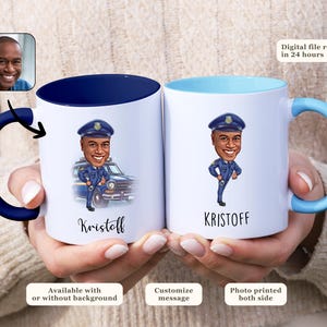 May include: Two white ceramic mugs with blue and light blue accents. Each mug features a cartoon illustration of a police officer and the name "Kristoff". The mugs are held by a person.