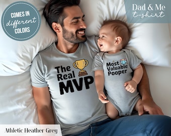 May include: Athletic heather grey t-shirts and onesie set. The adult shirt says "The Real MVP" with a trophy graphic. The baby onesie says "Most Valuable Pooper". The text "Dad & Me t-shirt" is also visible.