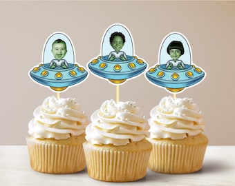 Könnte beinhalten: Drei Cupcakes mit weißem Frosting und Streuseln, die mit Cupcake-Toppern im Alien-Thema verziert sind. Jeder Topper zeigt ein Cartoon-Bild eines Kindergesichts in einem Raumschiff.