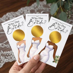 Puede incluir: Tres tarjetas blancas con el texto "Who Has The Bride?" y un círculo dorado para rascar. Cada tarjeta presenta un dibujo de una novia con un vestido de novia blanco. Una tarjeta tiene un ramo de flores.