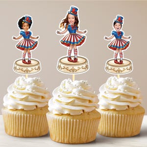 May include: Three cupcakes with white icing and sprinkles topped with personalised cupcake toppers featuring children dressed as circus performers. The toppers are on a round platform with a gold design.