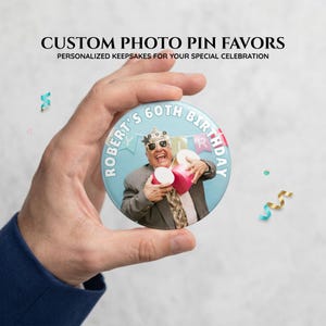 Puede incluir: Un botón de pin con foto personalizada redondo con fondo azul claro y el texto "ROBERT'S 60TH BIRTHDAY" en blanco. El centro muestra una fotografía de una persona con gafas de sol y un gorro de fiesta, sosteniendo cajas de regalo rosas.