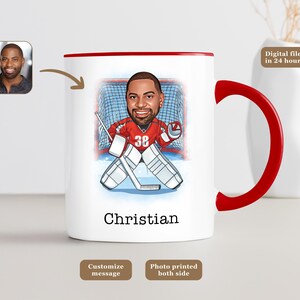 May include: White ceramic mug with a red handle and rim, featuring a cartoon illustration of a hockey goalie in red and white gear. The name "Christian" is printed below the image. A small photo of a man is in the upper left corner.