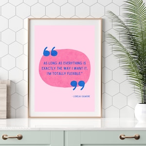 Pode incluir: Uma impressão artística emoldurada com fundo rosa e uma citação em texto azul: "AS LONG AS EVERYTHING IS EXACTLY THE WAY I WANT IT, I'M TOTALLY FLEXIBLE." A citação é atribuída a Lorelai Gilmore. A impressão é exibida em uma superfície branca.