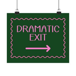 May include: A dark green sign with the words "DRAMATIC EXIT" in pink, along with a pink arrow pointing right. The sign has a pink, wavy border and is held by two black binder clips.