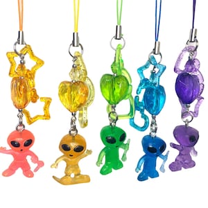 May include: Seven colorful alien keychains with different designs. Each keychain features a clear plastic alien figure with a different color and design. The keychains are attached to a string.