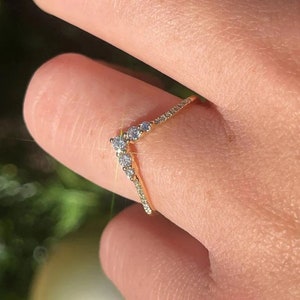 May include: A gold ring with a V-shaped design set with small diamonds.