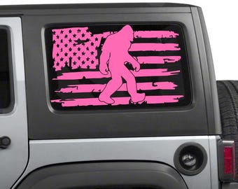 May include: A pink Bigfoot silhouette walking across a distressed American flag design, applied to a vehicle window. The flag features pink stars and stripes, creating a unique patriotic theme.